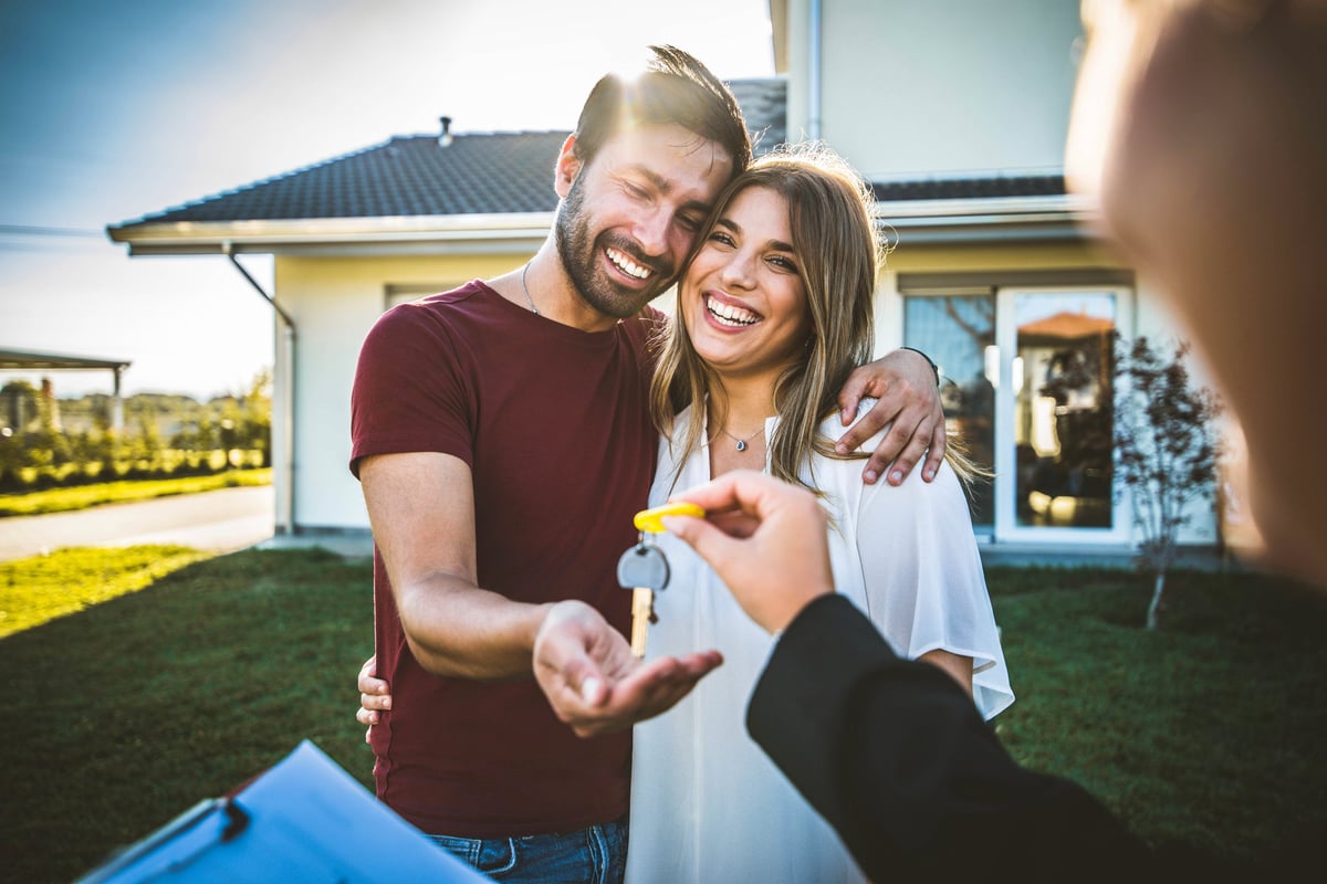 Happy millennial couple receiving keys from Real Estate Agent, purchasing real estate - Family meeting with real estate agent - New house and real estate concept