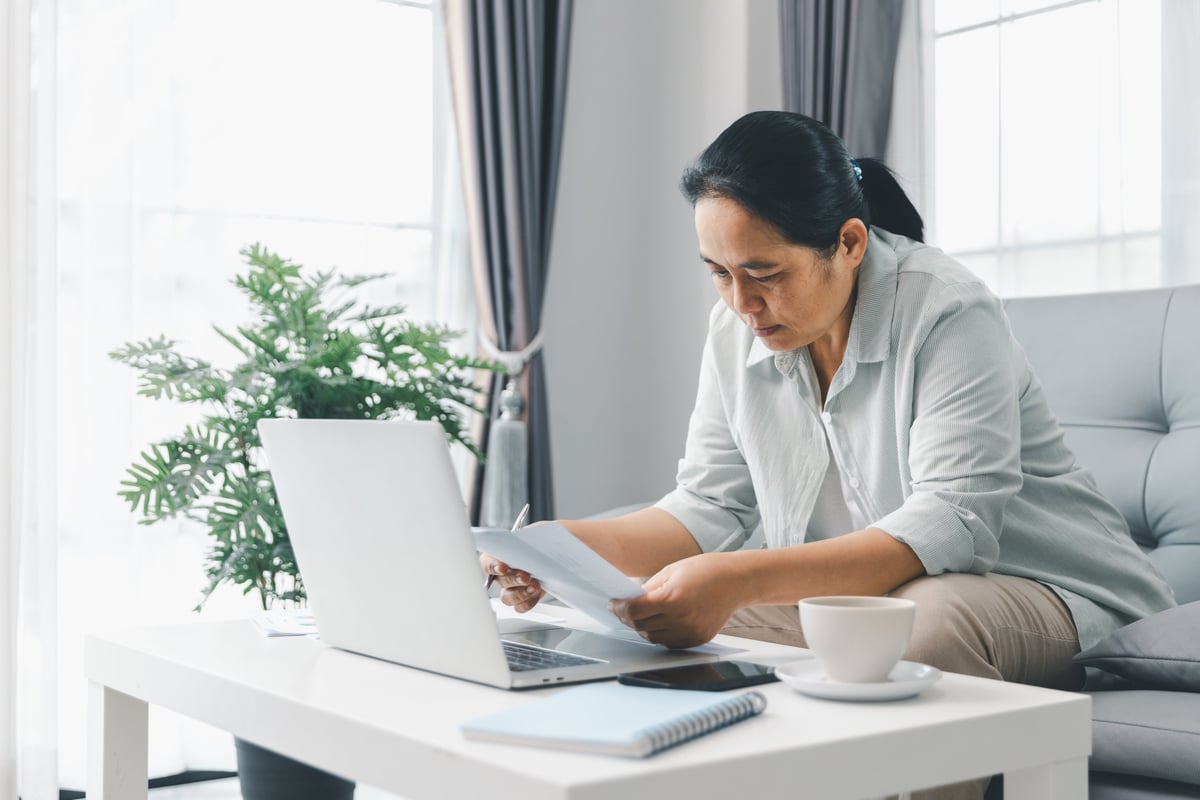 Woman working from home reviewing financial reports on laptop