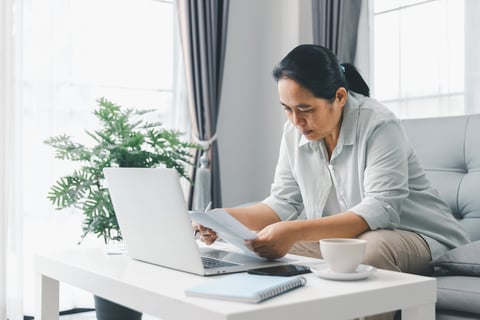 Woman working from home reviewing financial reports on laptop