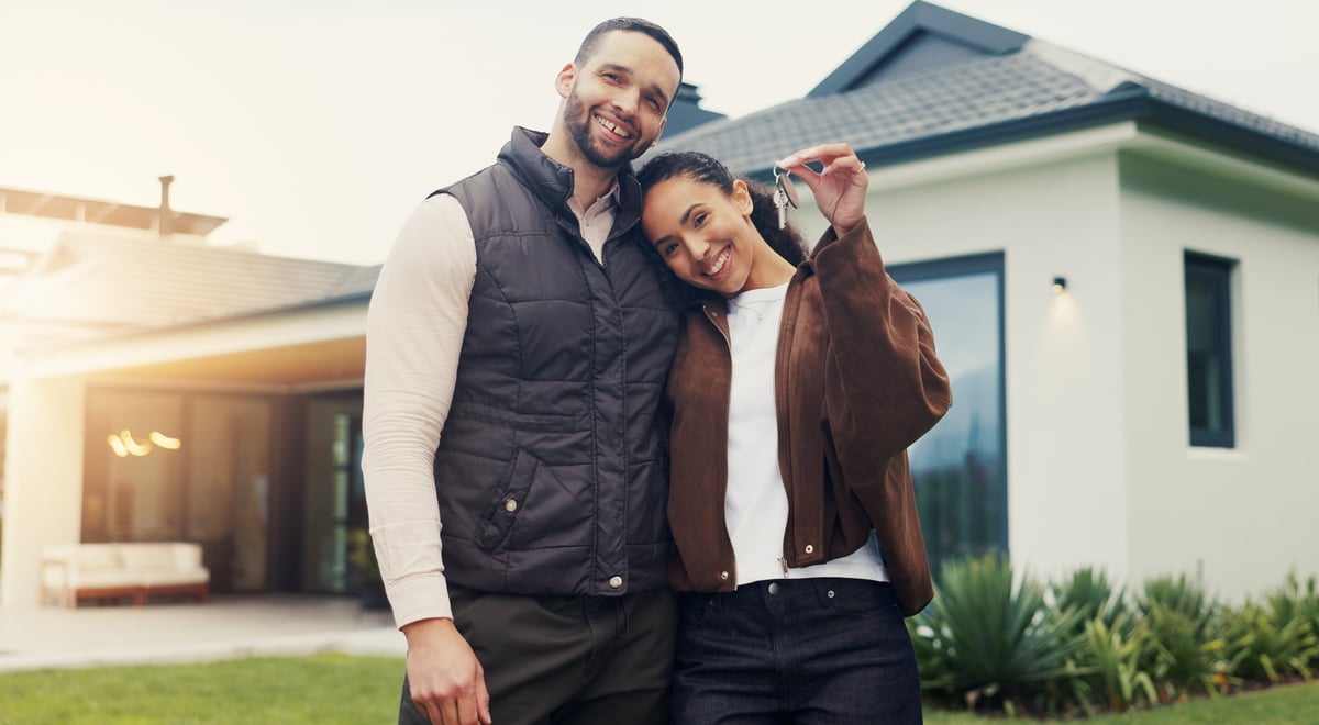 Happy couple with keys at their new home