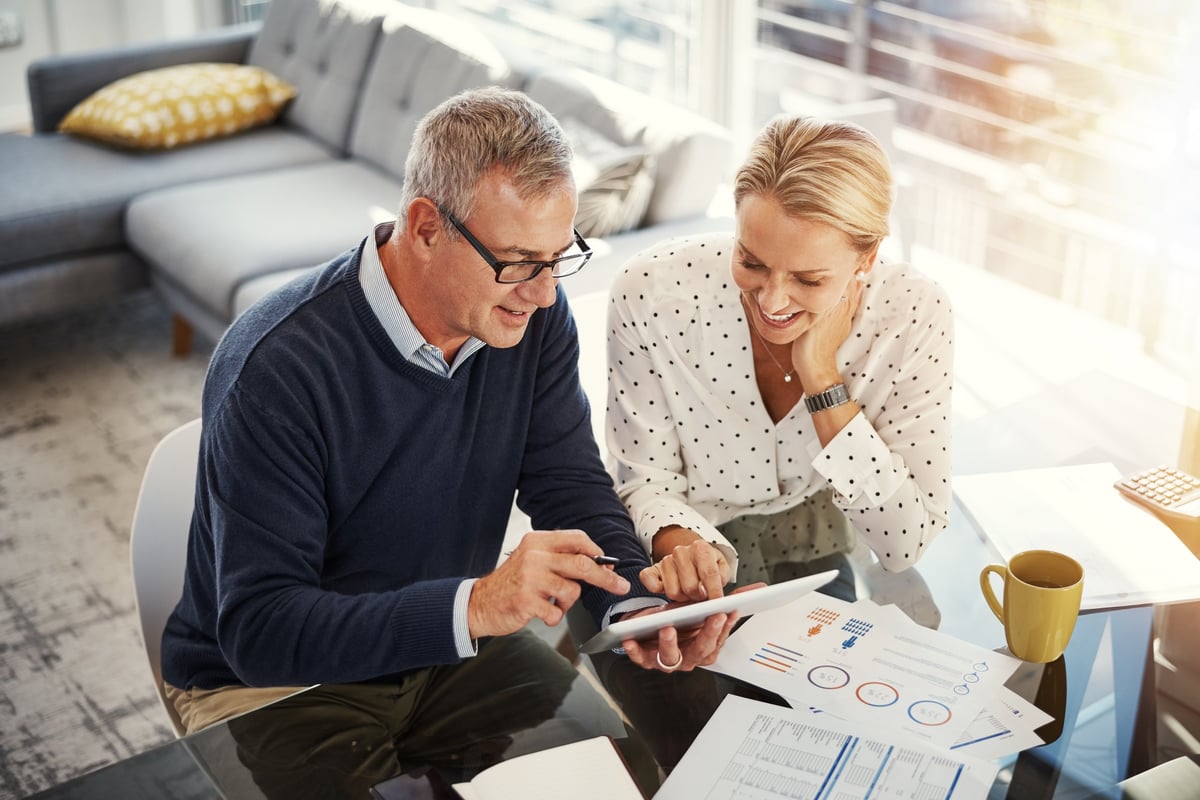 Mature couple using a digital tablet while going through paperwork at home