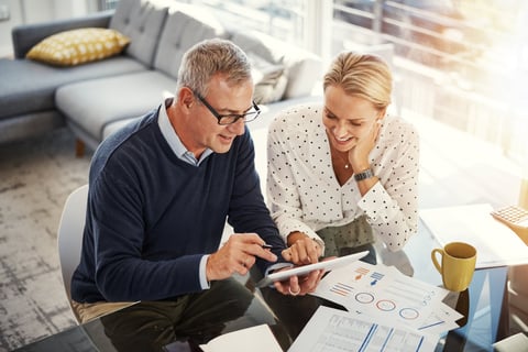 Mature couple using a digital tablet while going through paperwork at home